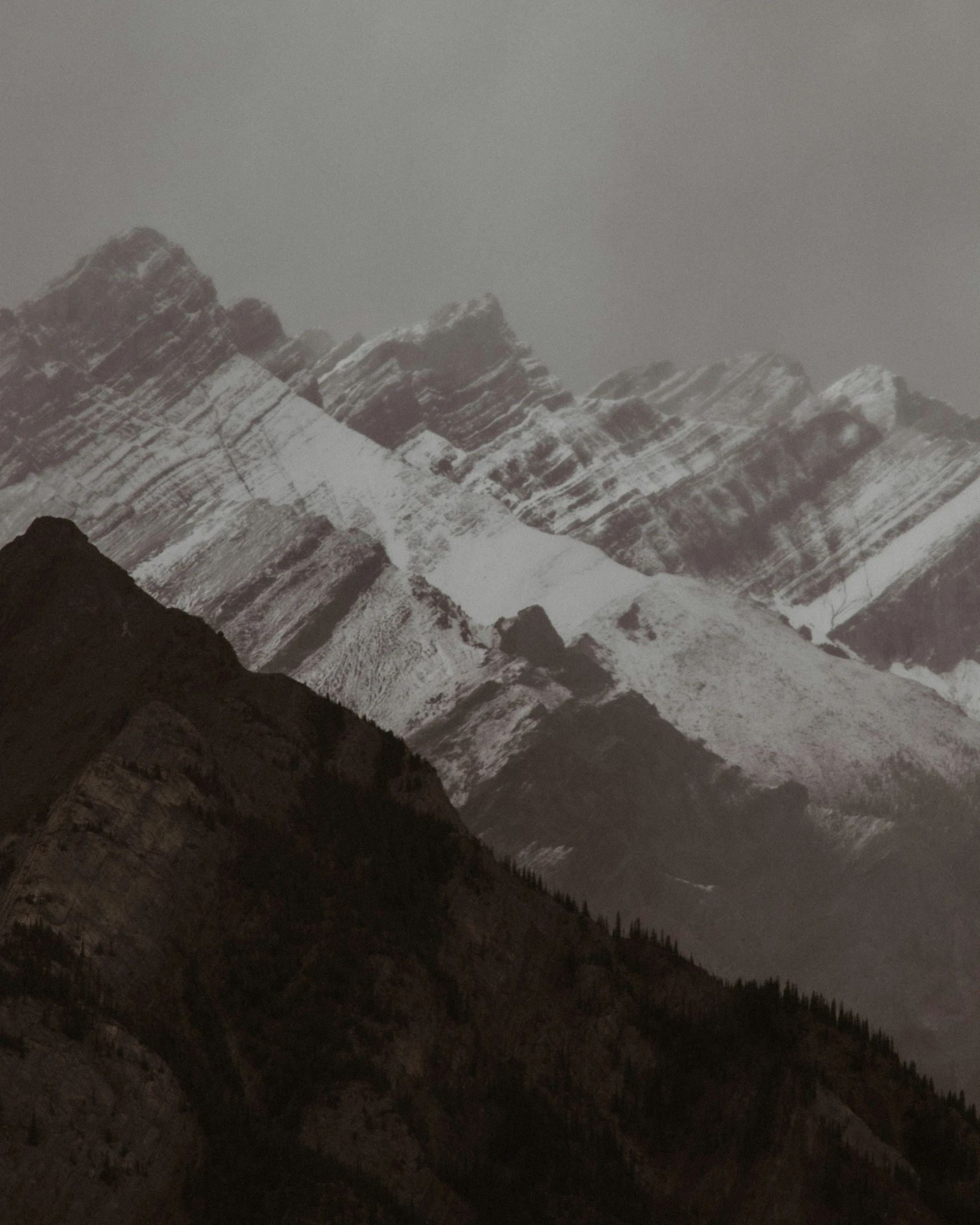 a mountain range covered in snow and covered in clouds