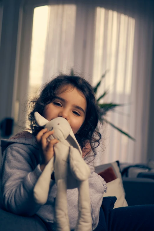 a little girl holding her teddy bear and looking at the camera