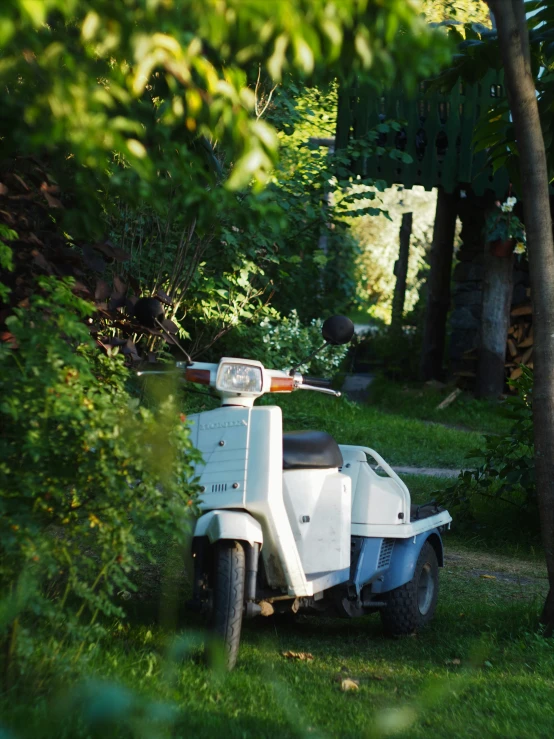 an old white motorcycle is parked near some trees