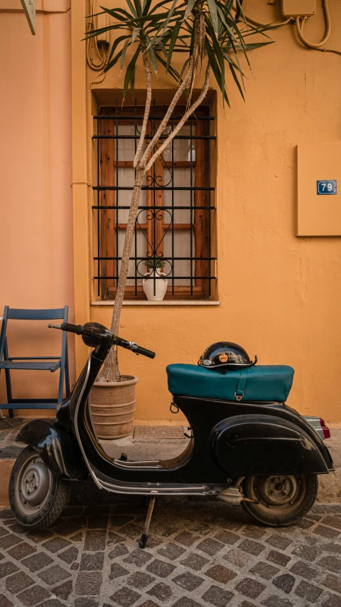 a moped is parked outside a building by a blue chair