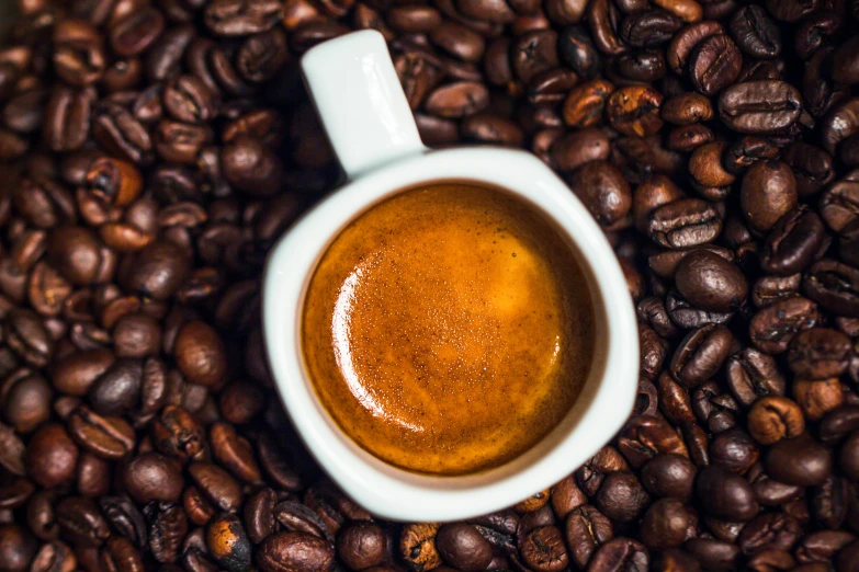 a cup of coffee on a bed of coffee beans