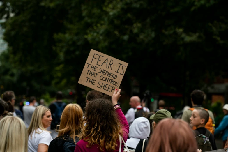 a protester holds up a sign that says fear is the subject of the conference