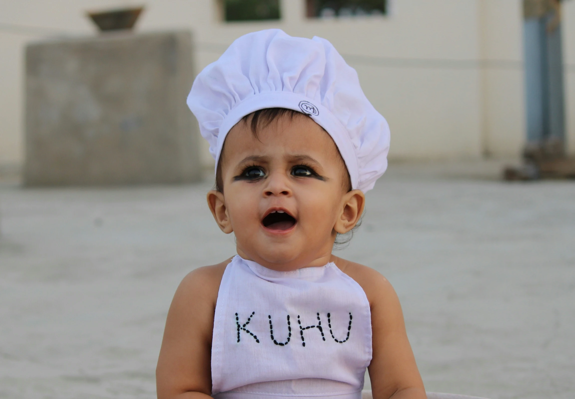 baby in bib sitting on tiled floor with sushi written on it