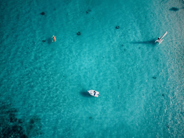 three small boats are in the middle of the ocean