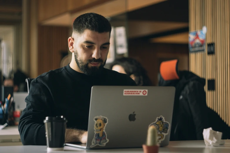 man using his computer while seated at the table