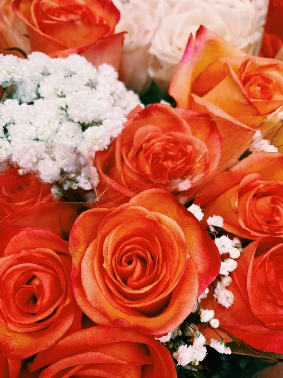 a bouquet of orange roses with white flowers in the center