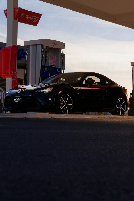 black sport car parked next to gas pumps