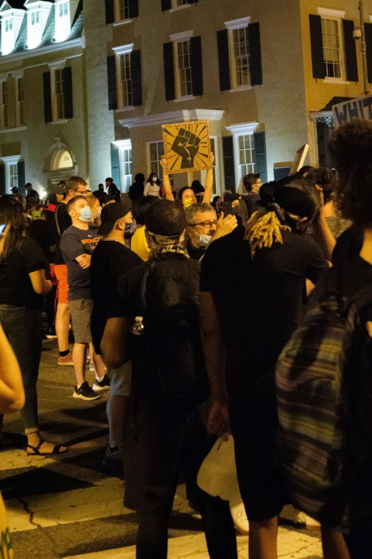 a crowd of people standing outside of a building at night