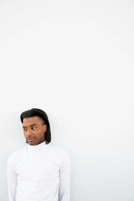 a young man in a white shirt standing with his head on his shoulder