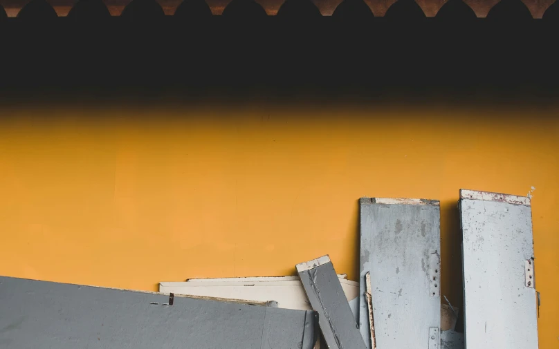 an old broken door frame is near an orange wall