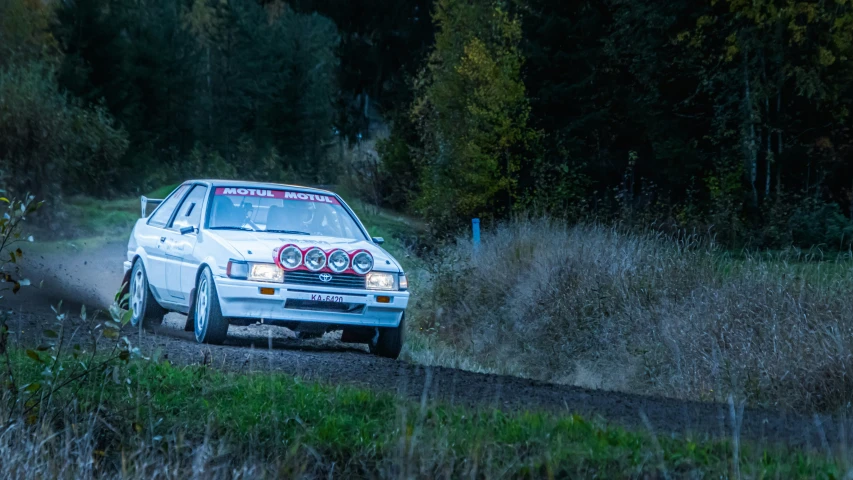 a white car on dirt road in grassy field