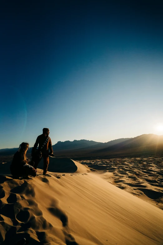 two people sitting in the sand on a beach