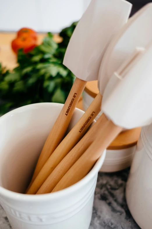 white ceramic cup holding several wooden utensils