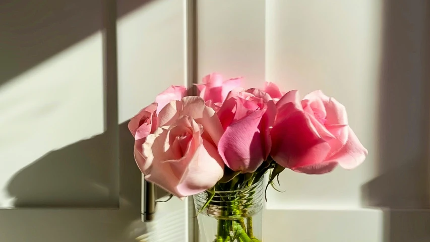 a glass vase filled with pink flowers sitting on a shelf