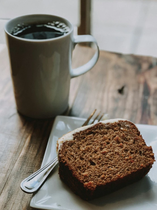 a table holding a piece of bread on a plate and cup of coffee