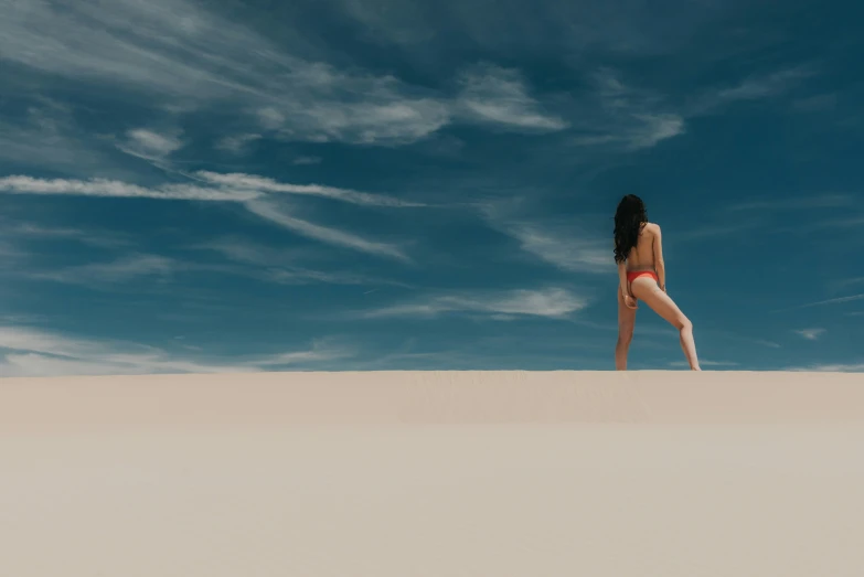 a woman walking across a white beach under a blue sky