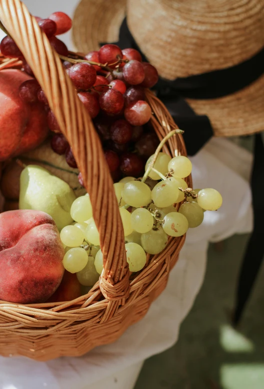 various fruit is shown in a basket next to a hat