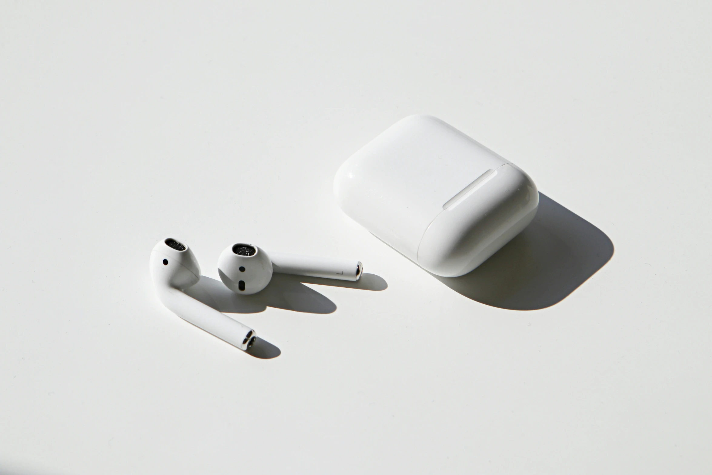 an overhead view of a pair of white earbuds and a black and white apple computer