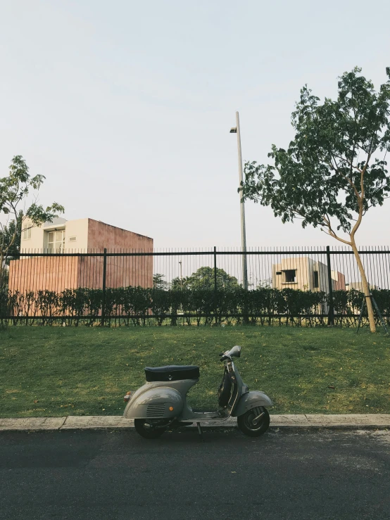 a scooter is parked by a fence and a road