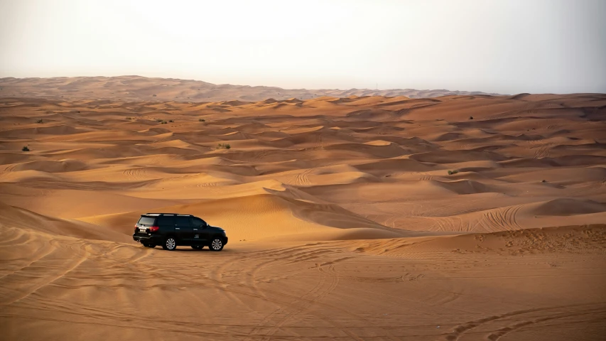 a suv driving through a sandy desert landscape