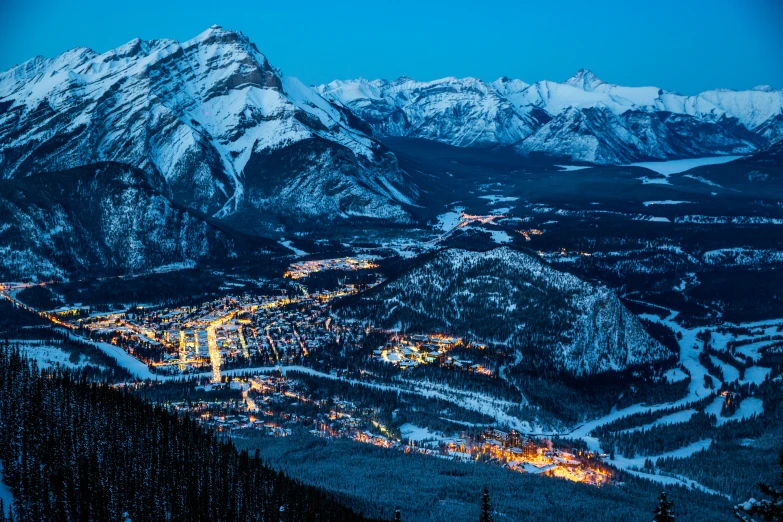 a snow capped mountain with lights and a valley