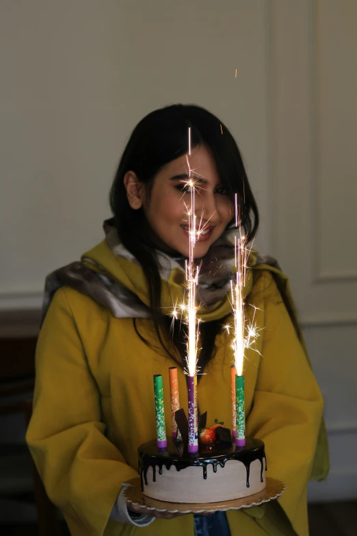 a woman with a sparkler in her hair while holding a cake