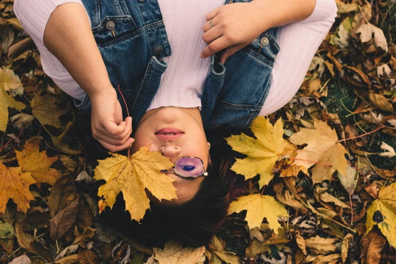 a girl laying on some leaves holding her lip