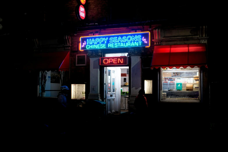 a dark street corner at night with a restaurant neon sign