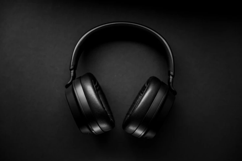 two wireless headphones sit side by side on a dark surface