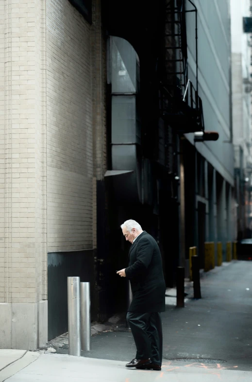 a man leaning up against a pole on the sidewalk