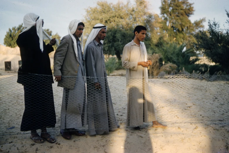 four men standing by a barbed wire fence