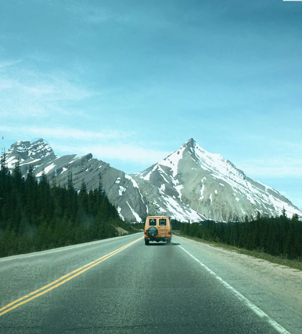 a bus traveling down a road near mountains