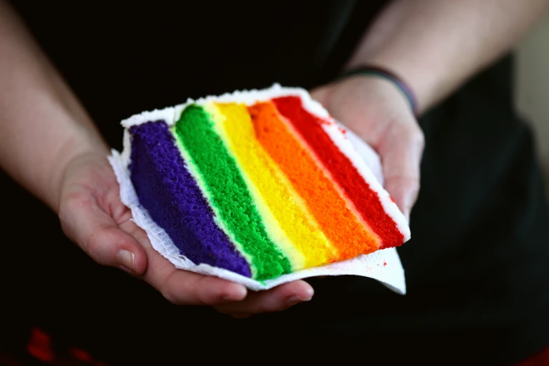 someone holding up a piece of cake with colorful frosting
