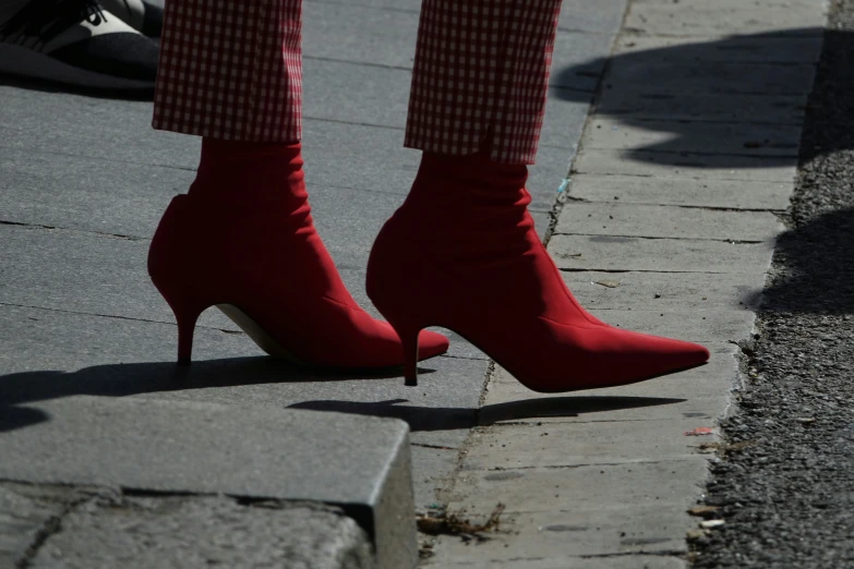 a woman's red boots are standing on the street