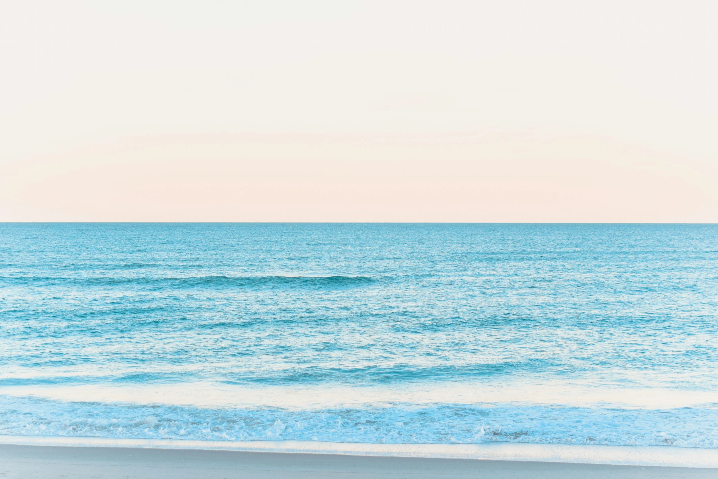 a surfer walking out to sea from an ocean beach