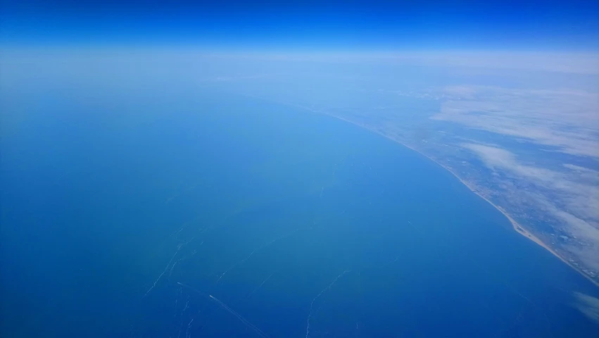 an aerial s of the sky and water with land