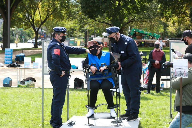 police officers standing around on the grass with a man sitting on top