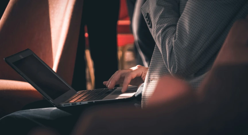 someone's hand using a laptop on their lap