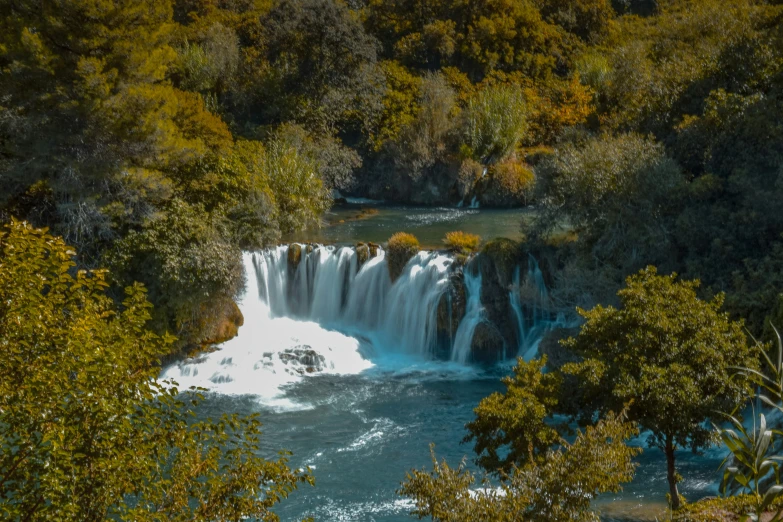 an aerial view of a waterfall in the middle of a forest