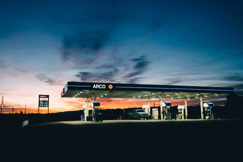 an empty gas station is shown against a dusk sky