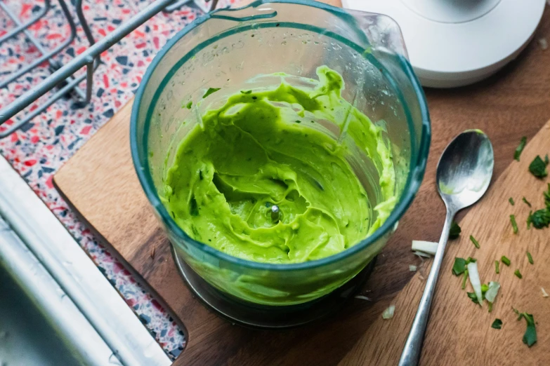 a green colored food blender sitting on top of a wooden table