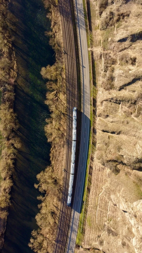 an aerial view of a blue train coming around a curve on a rail