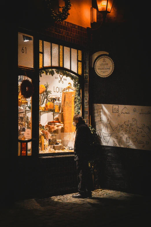 a person standing outside a shop window at night