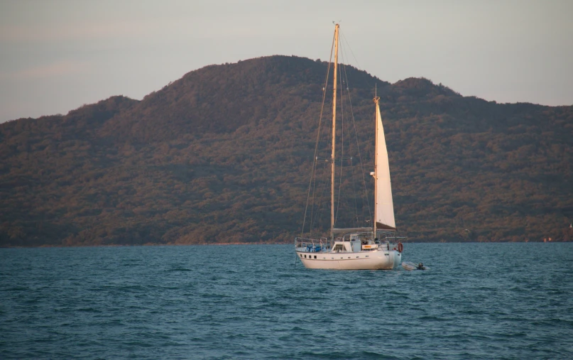 a sailboat traveling across the ocean by a mountain range