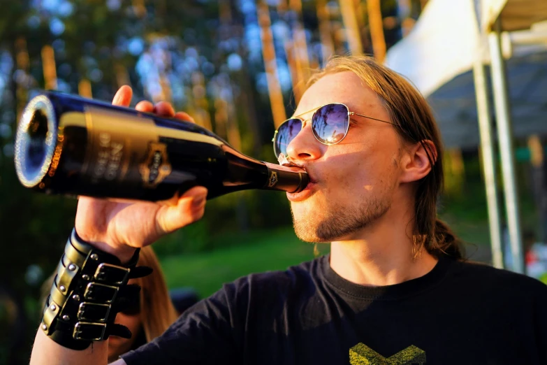 a man drinking some wine out of his wine bottle