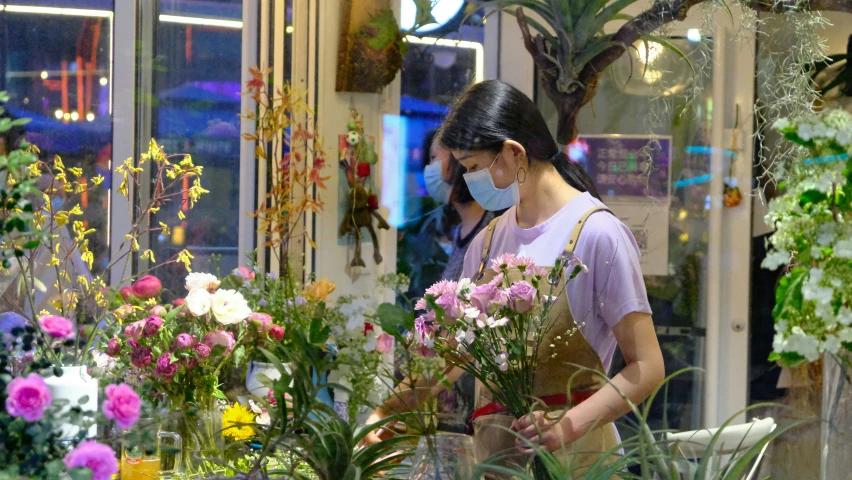 two women wearing masks looking at potted plants