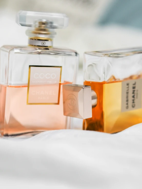 two bottles of perfume sitting on top of a bed