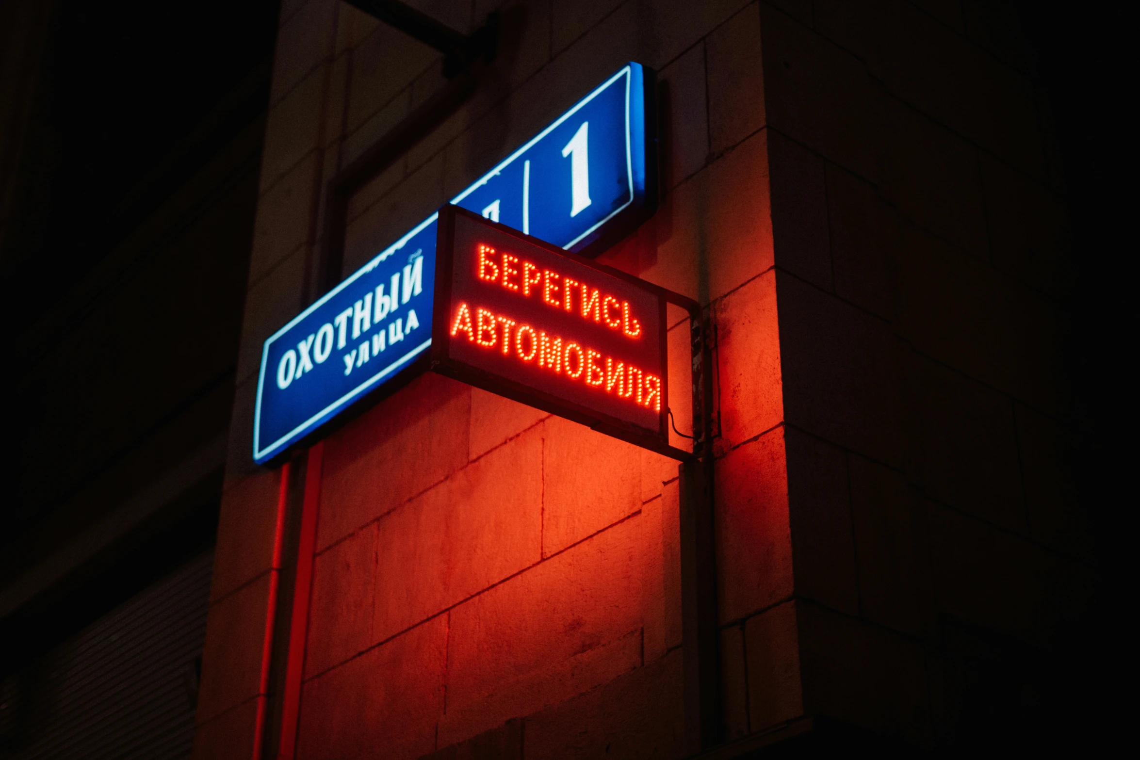 blue and red street signs attached to the side of a building