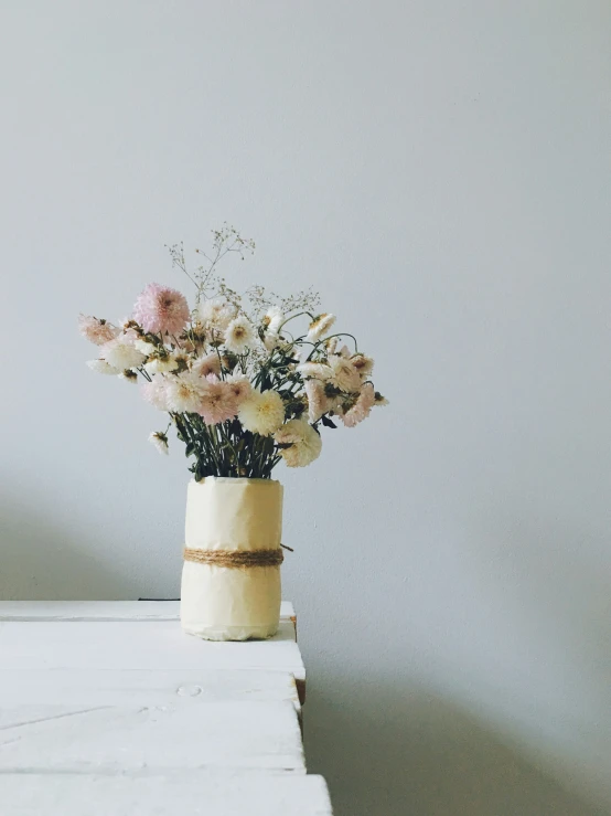 a flower pot with white, pink, and peach flowers