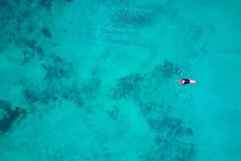 an aerial view of a red kayak and clear blue water